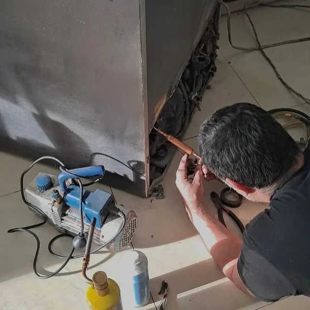 Soldadura de cañería con bomba de vacío durante una reparación de heladera
