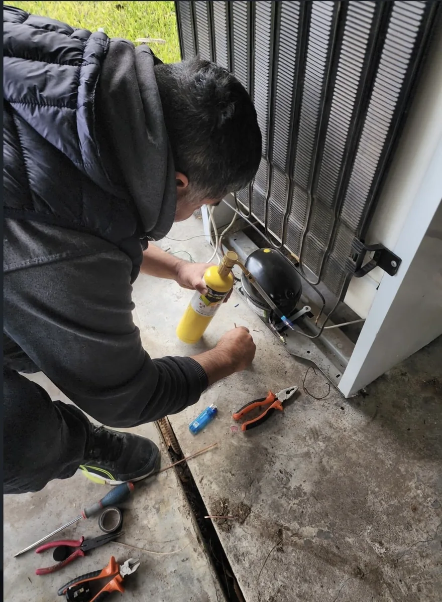 Técnico soldando la cañería del compresor de una heladera
