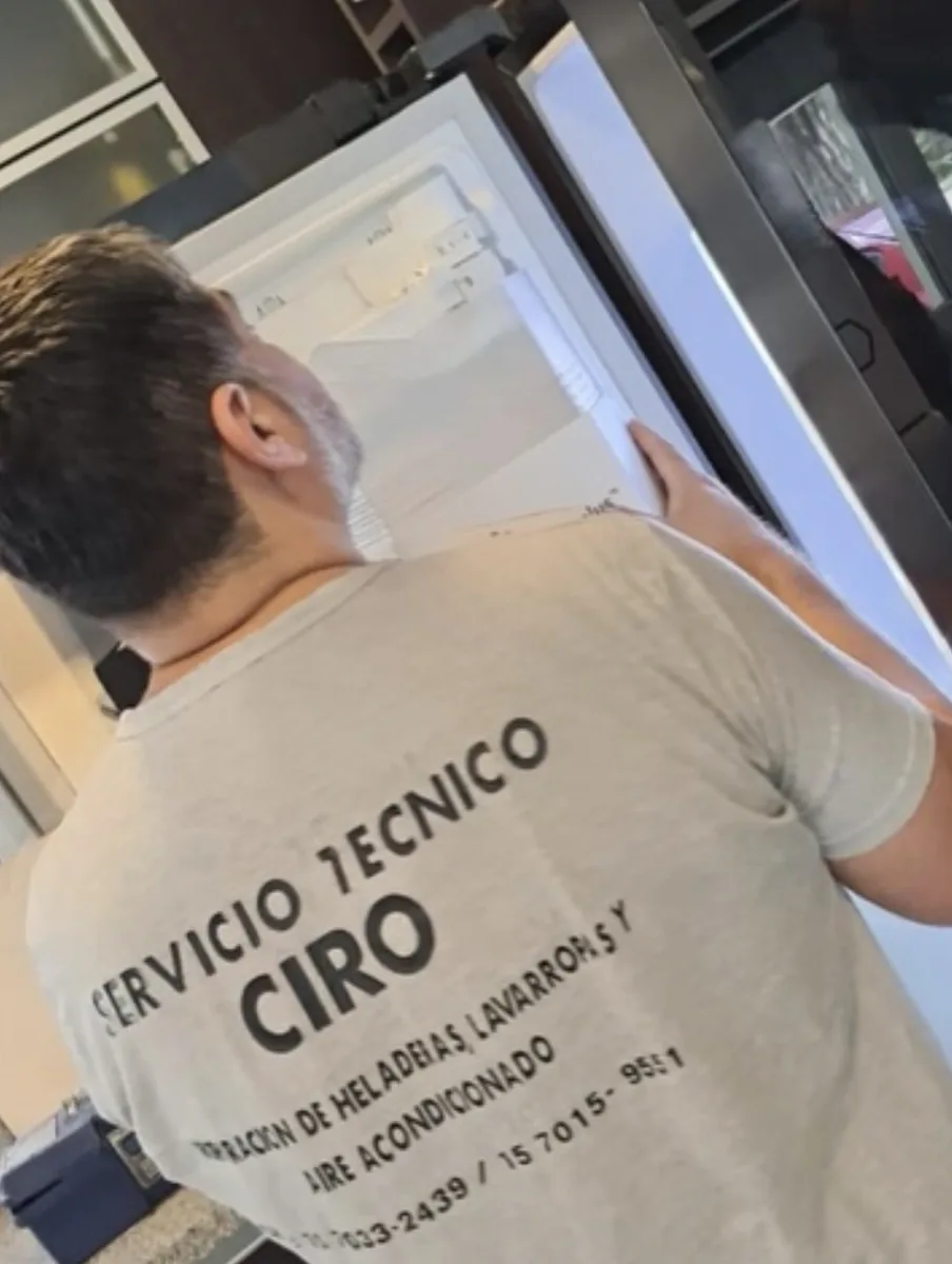 Técnico de Service Ciro, con el uniforme de la empresa, revisando una heladera en un domicilio